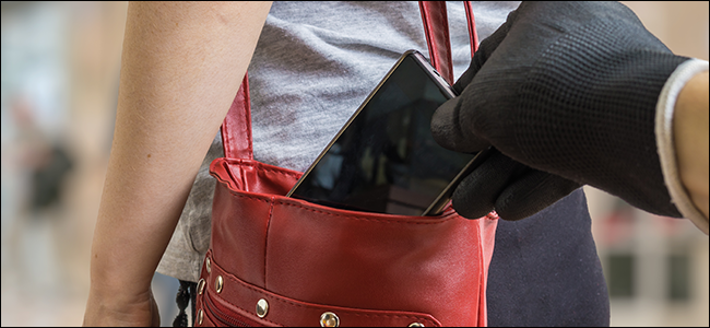 Uma mão enluvada roubando um telefone de uma bolsa.