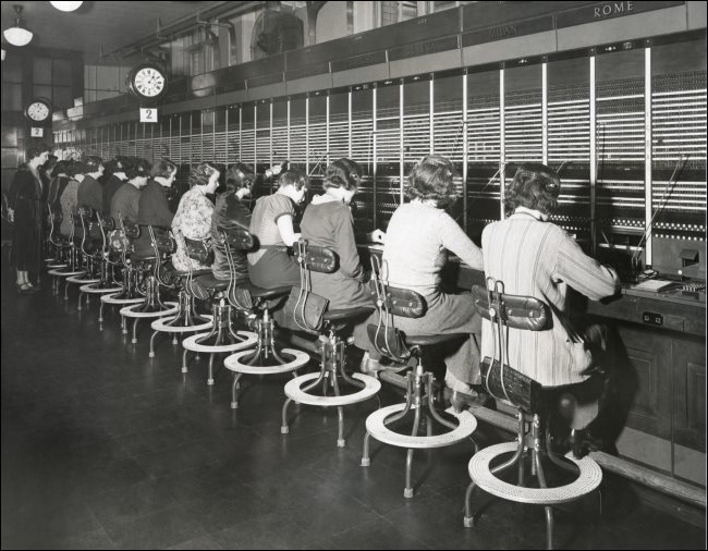 Operadoras de telefonia usando mesa telefônica na década de 1930.
