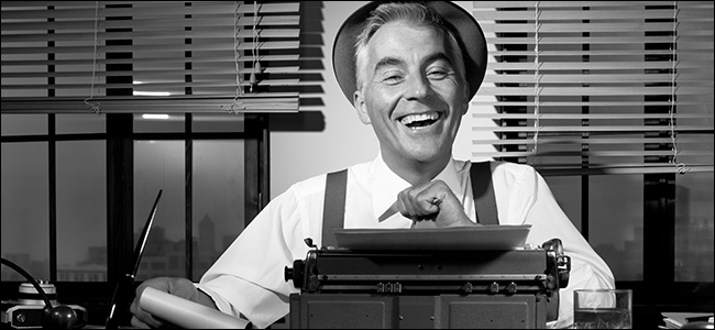 Um repórter dos velhos tempos ri atrás de uma máquina de escrever.