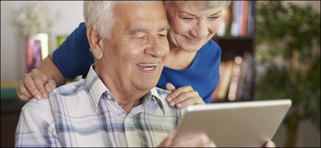 Casal de idosos sorrindo enquanto brincava com um tablet