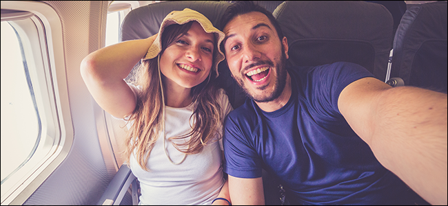 Um jovem casal tirando uma selfie em um avião