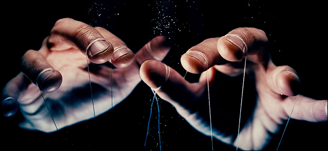 Um par de mãos com cordões de fantoches amarrados em cada dedo.