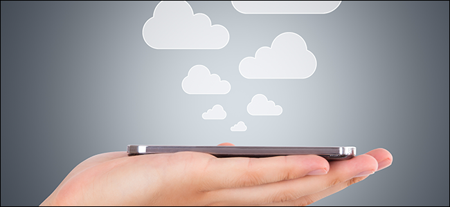 Uma mão segurando um telefone enquanto nuvens sobem dele, simbolizando arquivos sendo salvos na nuvem.
