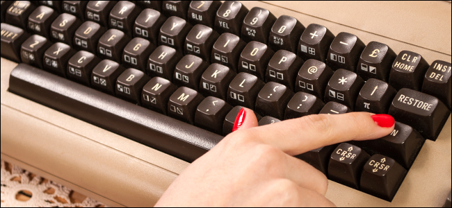 Uma mulher digitando em um teclado antigo.