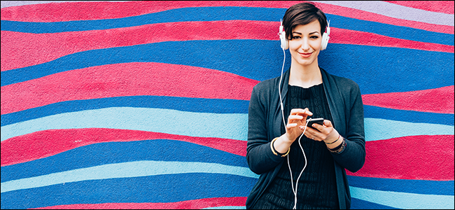 Uma mulher sorri enquanto ouve música com fones de ouvido