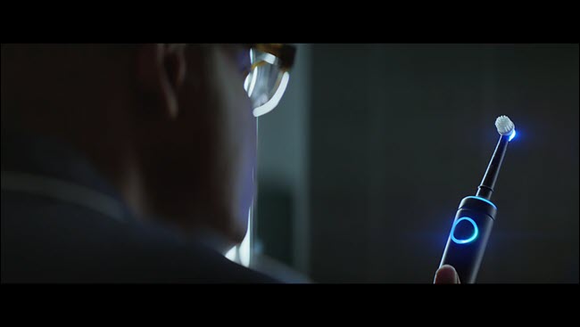 Homem do comercial de Alexa olhando para sua escova de dentes Echo iluminada.