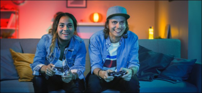 Um homem e uma mulher sentados em um sofá jogando videogame.