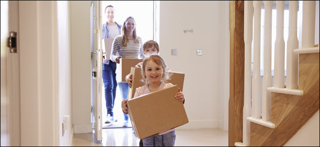 Uma família feliz carregando caixas para uma casa.