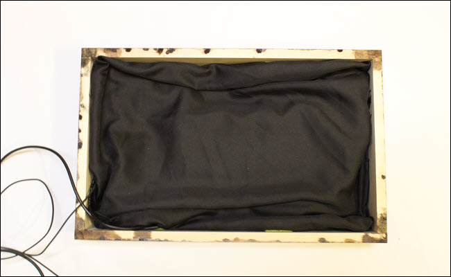 Caixa da moldura com pano preto drapeado.