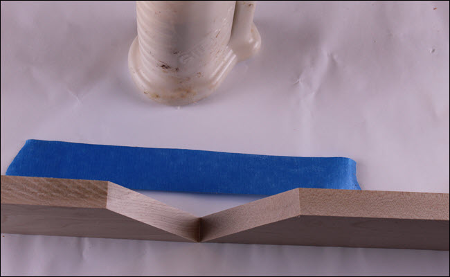 Duas pranchas com extremidades angulares se tocando, ao lado de uma tira de fita adesiva.