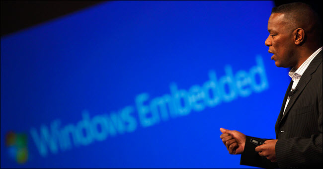 Homem falando na frente do logotipo do Windows Embedded.