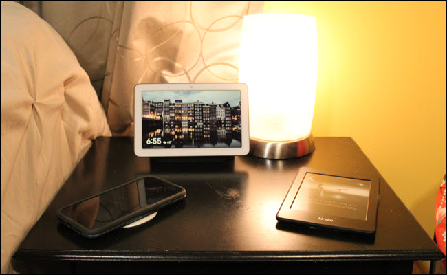 Nest Hub, Kindle e iPhone em um suporte noturno.