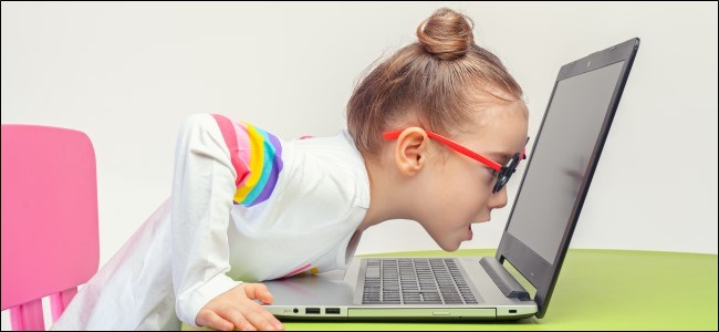 Criança de óculos encostada no laptop