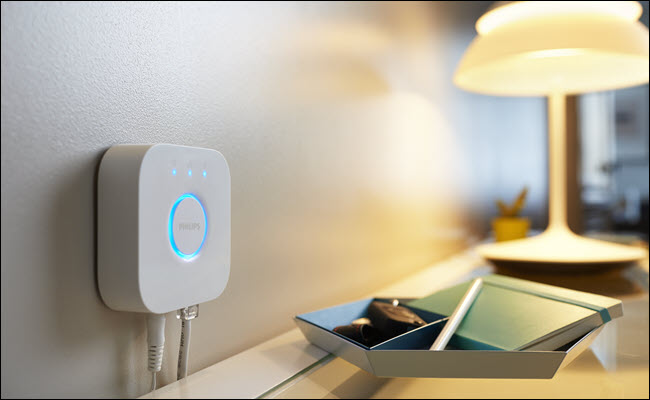 Hub Philips Hue próximo a uma lâmpada em uma cômoda.