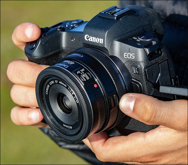 Alguém segurando uma câmera Canon EOS com um adaptador sem espelho montado nela.