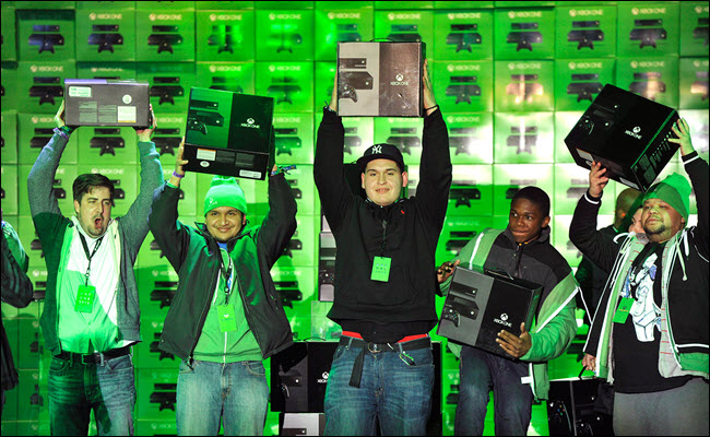 Vários concorrentes da Microsoft segurando novos consoles do Xbox One no dia do lançamento