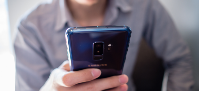 homem segurando um telefone Android azul