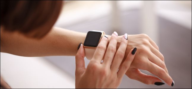 Uma mulher pressionando o botão lateral de um Apple Watch que está usando.