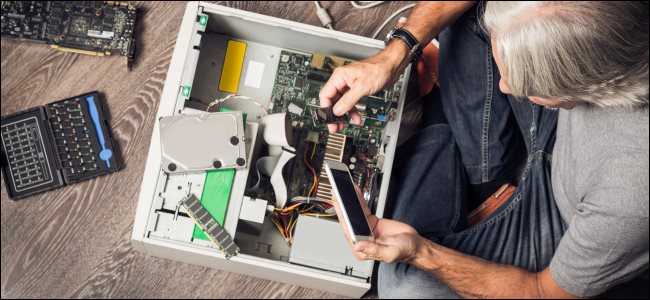 Um homem montando um computador desktop no chão.