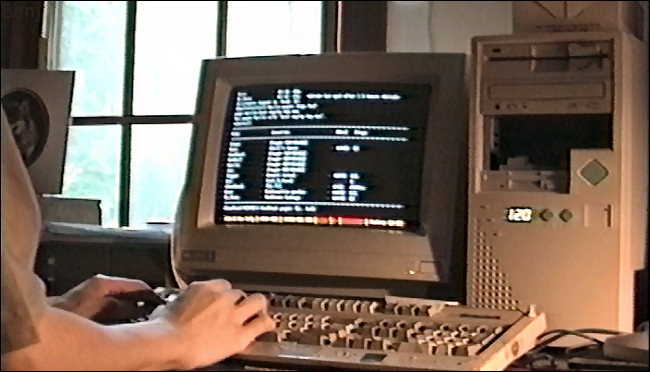 Mãos digitando no teclado de um computador vintage, com um MUSH na tela.