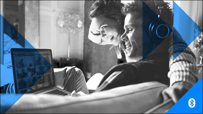 Um homem e uma mulher usando fones de ouvido enquanto olha para a tela de um computador laptop.