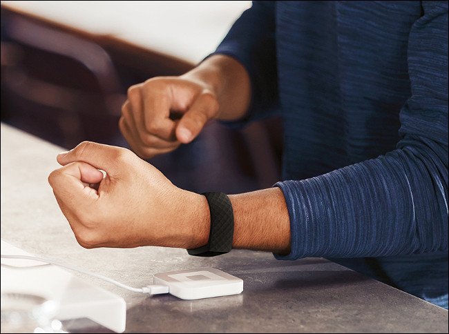 Um homem carregando um Fitbit Charge 4.