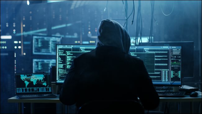 Um hacker sombrio com um moletom sentado na frente de um computador.