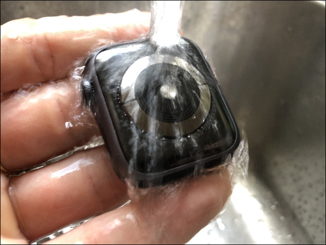Um Apple Watch sendo lavado em água corrente.