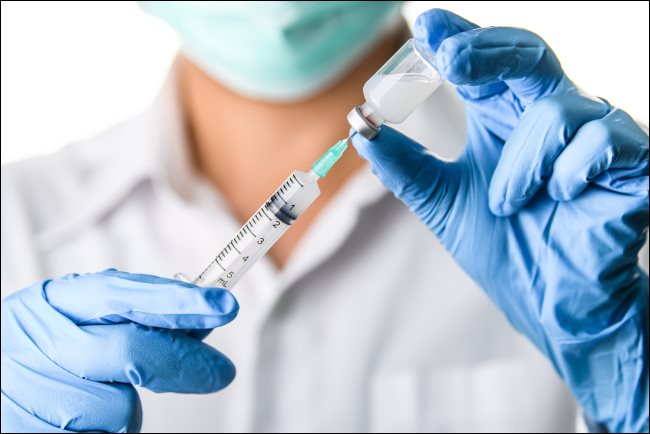 Um médico ou enfermeira se preparando para injetar uma vacina.