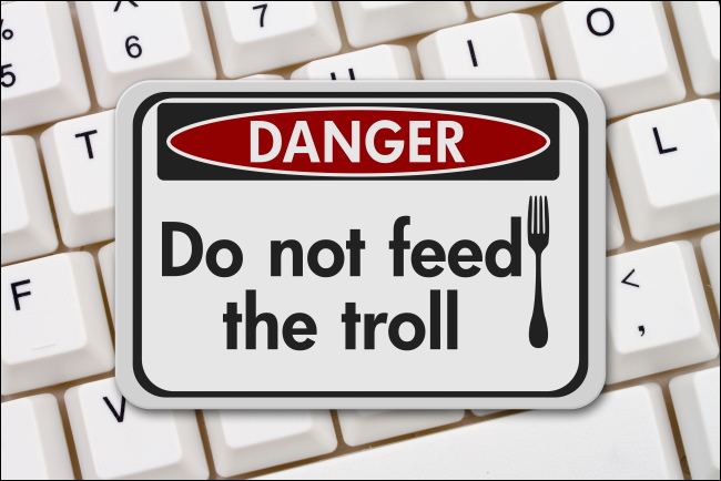 Uma placa de "Perigo: Não alimente o troll" no teclado de um computador.