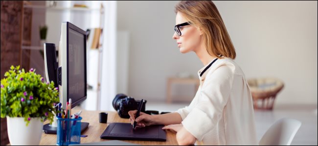 Uma mulher que trabalha com uma mesa digitalizadora em um computador.