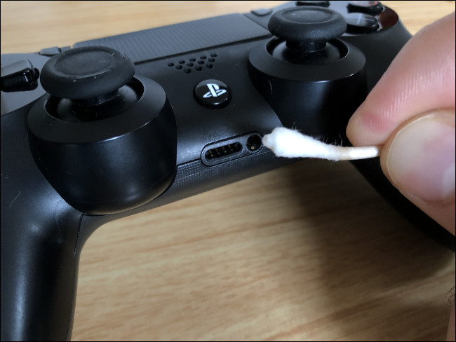 Um Q-tip limpando uma porta em um Controlador DualShock 4.