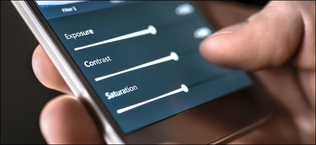 Alguém ajustando os controles deslizantes de "Exposição", "Contraste" e "Saturação" em um smartphone.