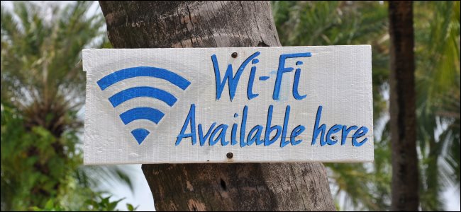Uma placa de "Wi-Fi disponível aqui" afixada em uma árvore.