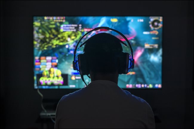 Um jovem jogador jogando um jogo para PC usando fones de ouvido.