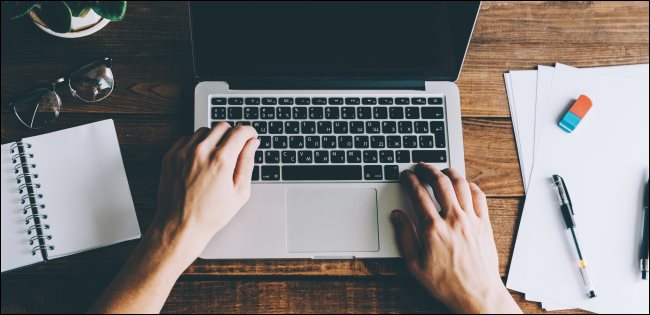 Mãos digitando em um laptop.