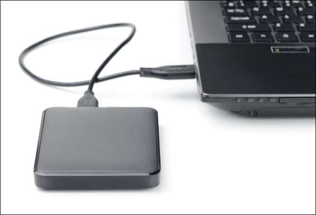 Um disco rígido externo conectado a um laptop por meio de um cabo USB.