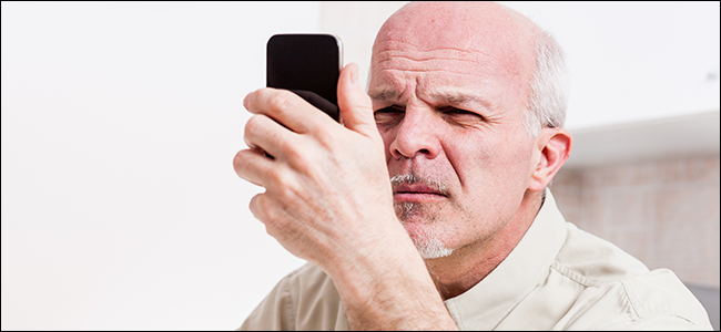 Um homem encara seu telefone, claramente sofrendo de um sério cansaço visual.