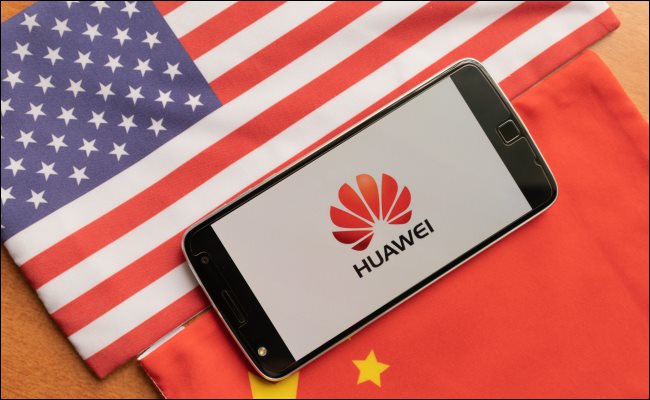 Um telefone Huawei entre uma bandeira dos EUA e da China.