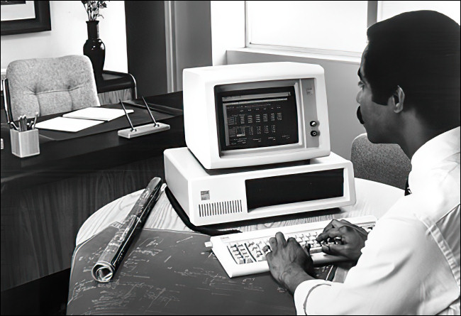 Um homem trabalhando em um IBM PC 5150.