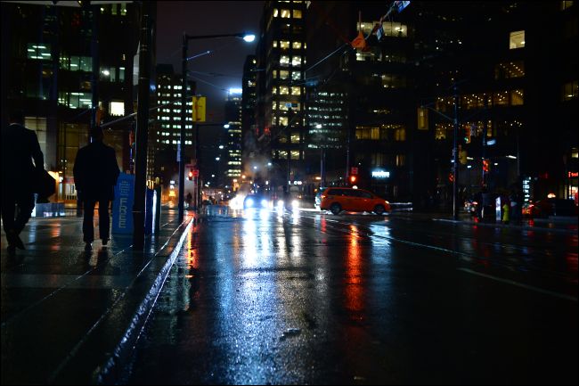 Pessoas andando pelas ruas de Toronto à noite na chuva