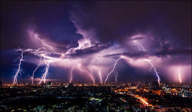 Tempestade com relâmpagos sobre a cidade em luz roxa