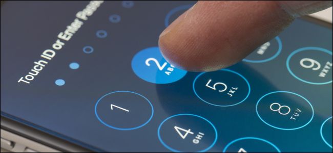 O dedo de uma pessoa digitando uma senha na tela de bloqueio do iPhone