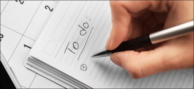 Mão escrevendo uma lista de tarefas em um caderno.