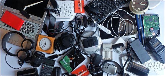 Uma pilha de eletrônicos usados, incluindo um laptop, fones de ouvido, mouse e teclado.