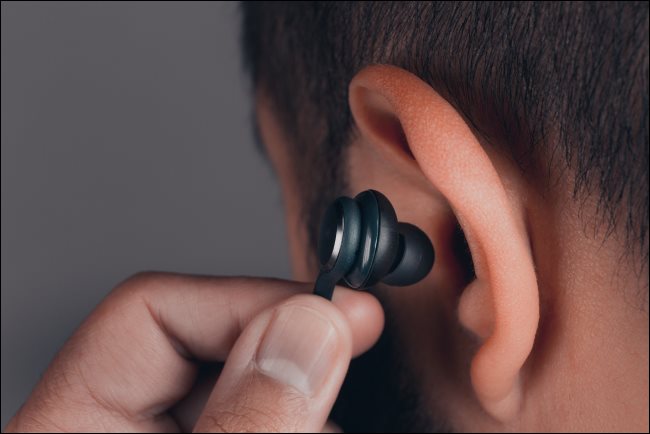 Um homem inserindo um fone de ouvido no ouvido.