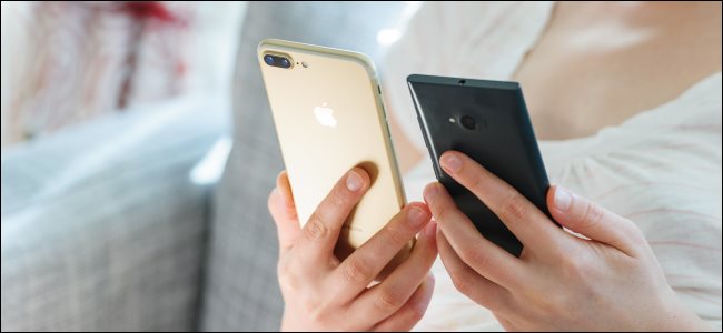 Uma mulher segurando um iPhone e um telefone Android.