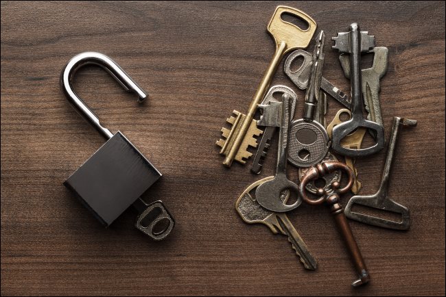 Várias chaves ao lado de um cadeado aberto.