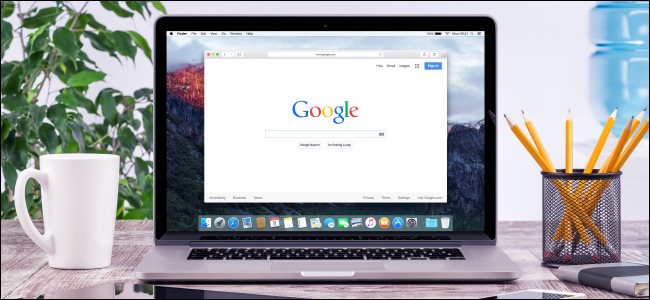 Um MacBook com pesquisa do Google na tela, sentado em uma mesa ao lado de uma caneca de café e um copo de lápis.