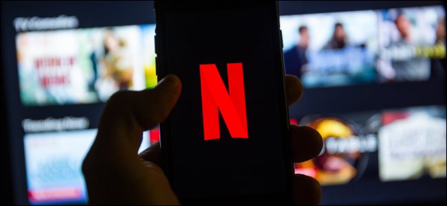 O logotipo da Netflix em um smartphone na frente da Netflix em uma smart TV.